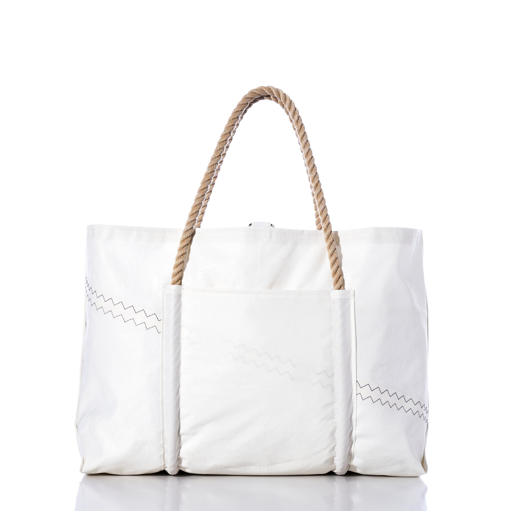The U.S. Yacht Ensign Wharf Tote by Sea Bags is a large white canvas bag with rope handles, zigzag stitching details, and an exterior front pocket, photographed against a white background. Inspired by nautical style and crafted from recycled sail cloth, this tote showcases sustainable craftsmanship in every detail. by Sea Bags