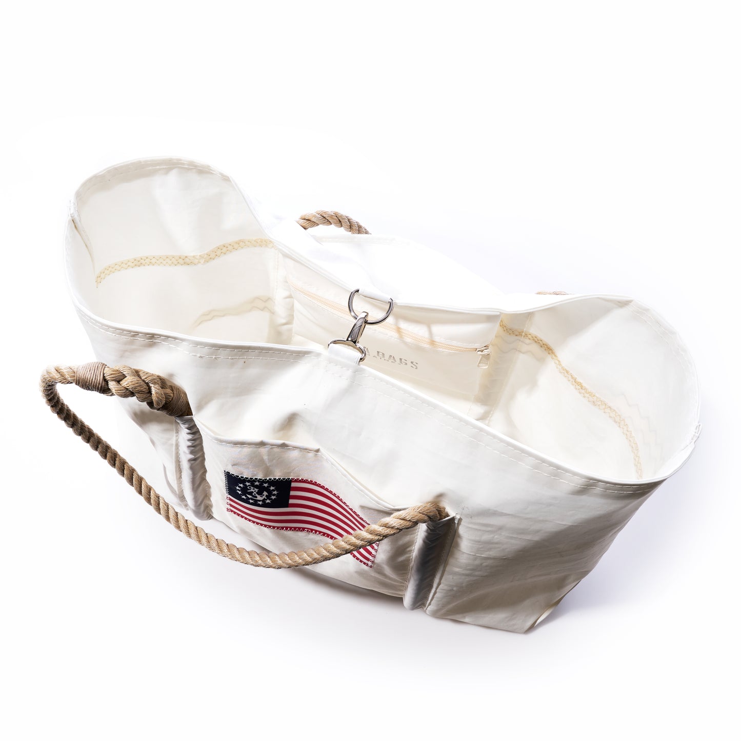 Introducing the Sea Bags U.S. Yacht Ensign Wharf Tote—a white canvas tote featuring rope handles, a metal clasp, and an embroidered American flag patch on the front, combining nautical style with sustainable craftsmanship. by Sea Bags