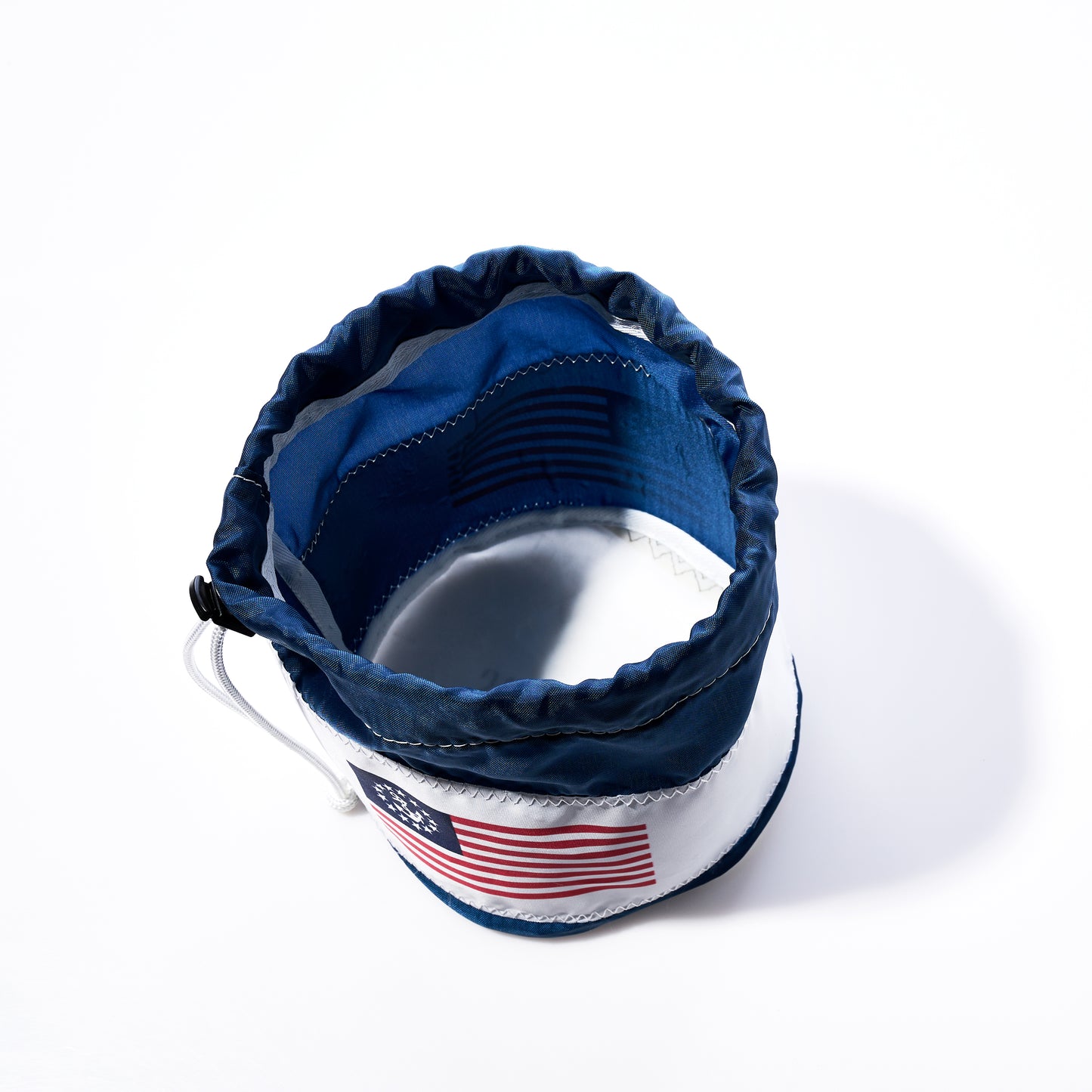 The U.S. Yacht Ensign Ditty Bag by Sea Bags—a cloth pouch made from recycled sail cloth bags—features a blue-edged design, a drawstring closure, and an American flag patch, and is photographed from above on a white background. by Sea Bags