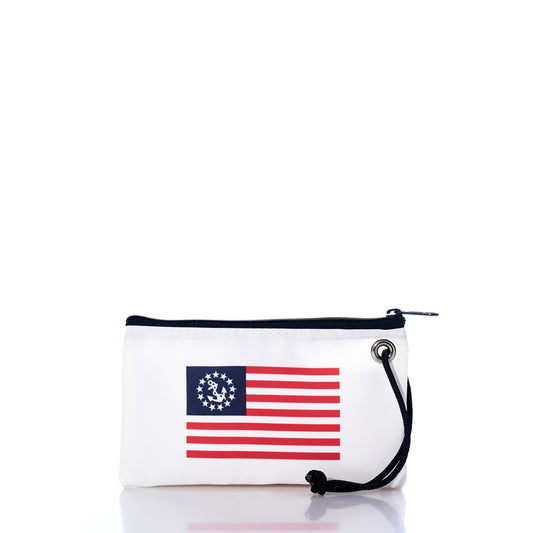 Introducing the Sea Bags U.S. Yacht Ensign Wristlet—a small white zippered pouch crafted from recycled sail cloth for sustainable style. Showcasing a printed design inspired by the classic Betsy Ross American flag, it features 13 stars arranged in a circle and 13 red and white stripes. Finished with a practical black wrist strap, this accessory channels timeless nautical flair. by Sea Bags