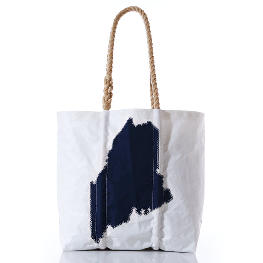 The Navy State of Maine Medium Tote by Sea Bags features rope handles and a bold navy silhouette of Maine on the front, making it the perfect Pine Tree State accessory or a thoughtful gift for anyone who loves the coast. by Sea Bags