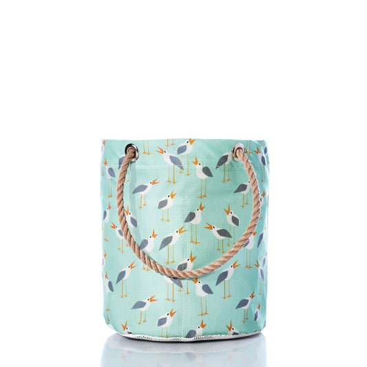 Introducing the Sea Bags Wharf Gulls Beachcomber Bucket—a light blue fabric tote with rope handles, adorned with a repeating pattern of stylized seagulls and yellow beaks on a white background. This charming beach bag features durable construction inspired by recycled sail cloth, making it perfect for seaside adventures while capturing a breezy coastal feel. by Sea Bags