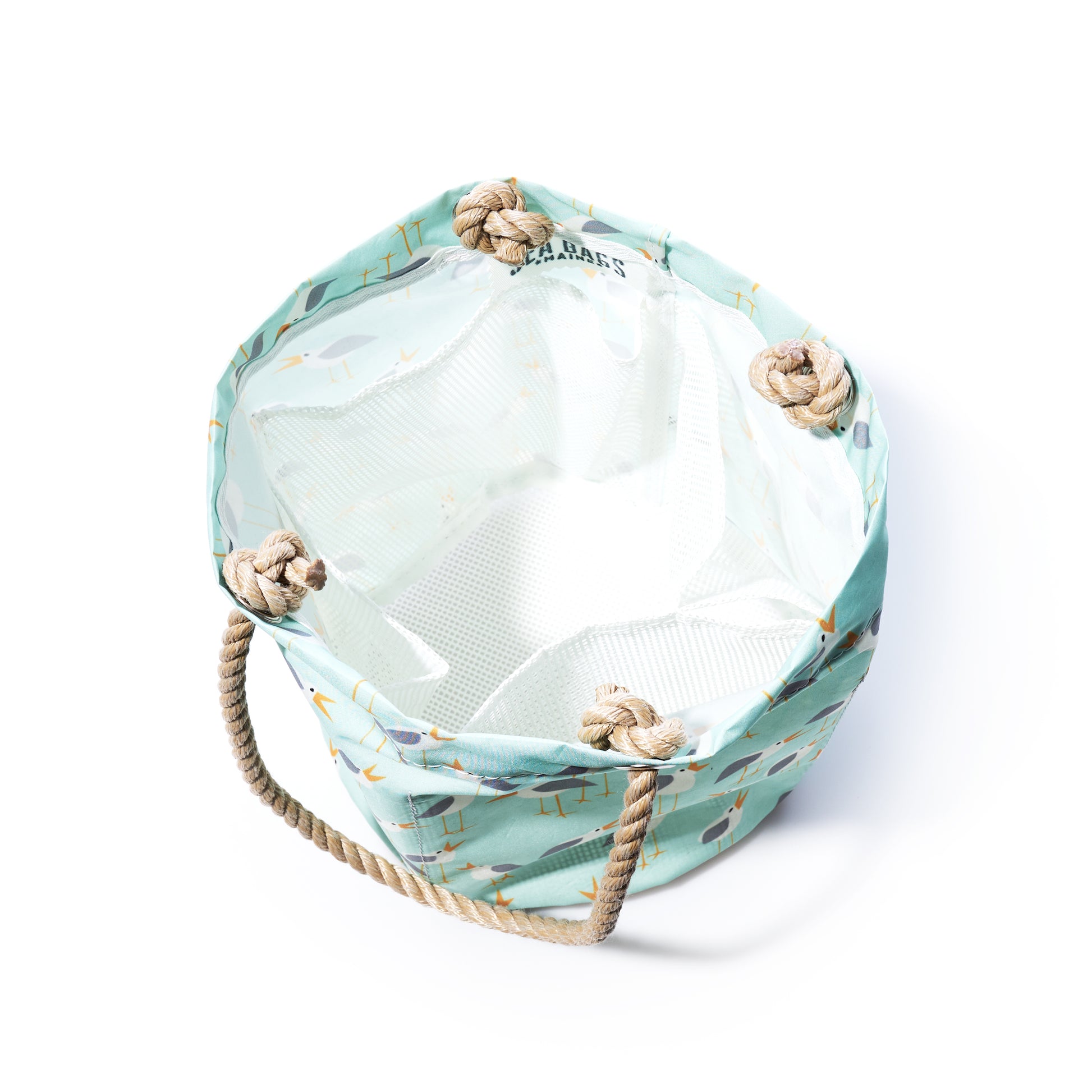 The Sea Bags Wharf Gulls Beachcomber Bucket is a cylindrical fabric bag crafted from recycled sail cloth, featuring a light blue patterned exterior, tan rope handles, and a white interior. Shown from above on a white background, it makes a stylish beach bag option. by Sea Bags