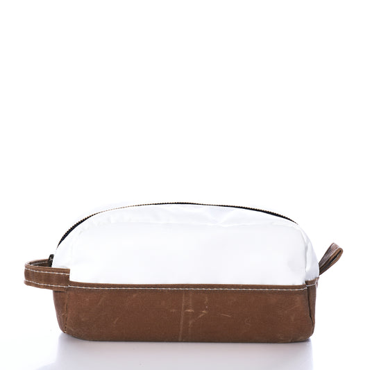 Introducing the Tan Chebeague Toiletry Bag by Sea Bags—a compact zippered pouch made from durable waxed canvas, featuring a white top, brown base, and convenient side handle, pictured against a plain white background. Ideal for those who appreciate seaworthy travel bags. by Sea Bags