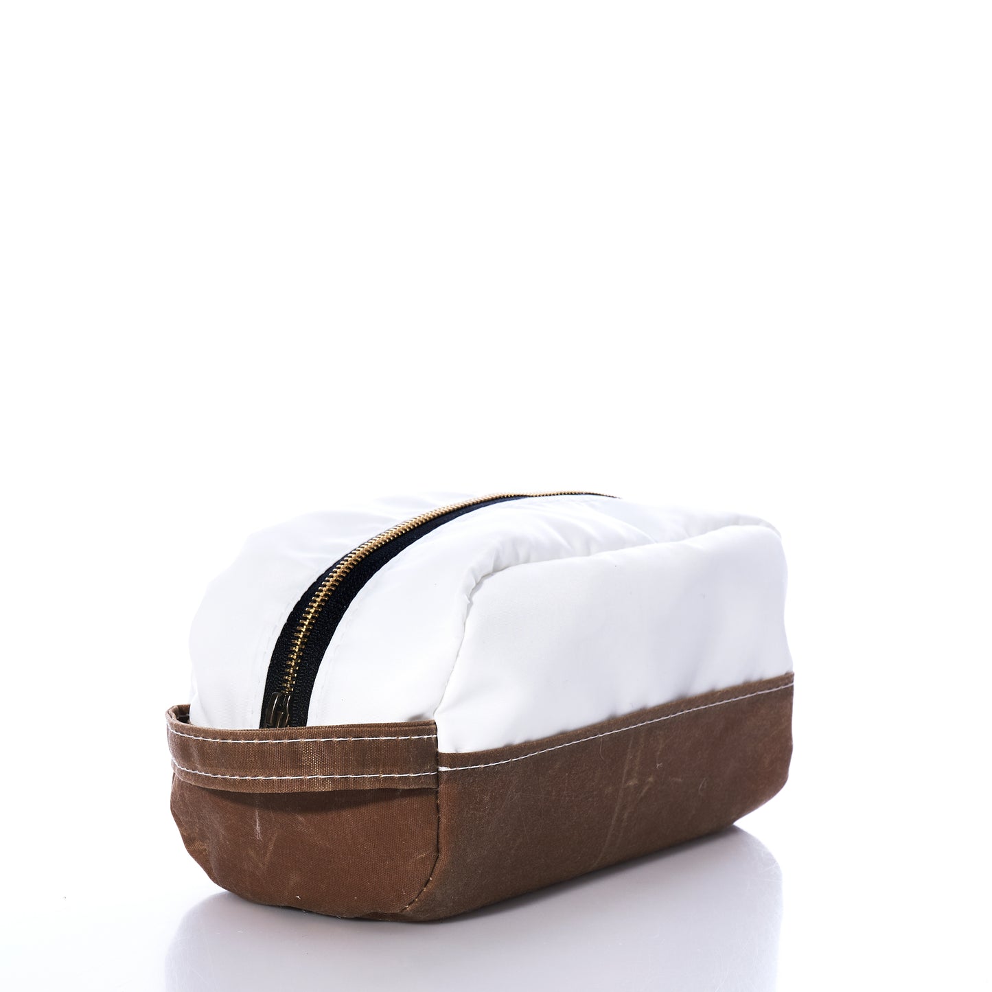 The Tan Chebeague Toiletry Bag by Sea Bags features a rectangular silhouette with a white top and brown waxed canvas base, accented by a visible zipper closure. Set against a white background, its durable design is inspired by seaworthy travel bags—offering both function and style. by Sea Bags