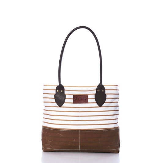 Introducing the Tan Chebeague Stripe Handbag from Sea Bags—a nautical-inspired tote crafted from recycled sail cloth. This stylish bag features a brown base and handles, with horizontal beige and white stripes adorning the upper section. Finished with a small leather patch on the front, it offers a timeless touch of classic charm inspired by Chebeague Island. by Sea Bags