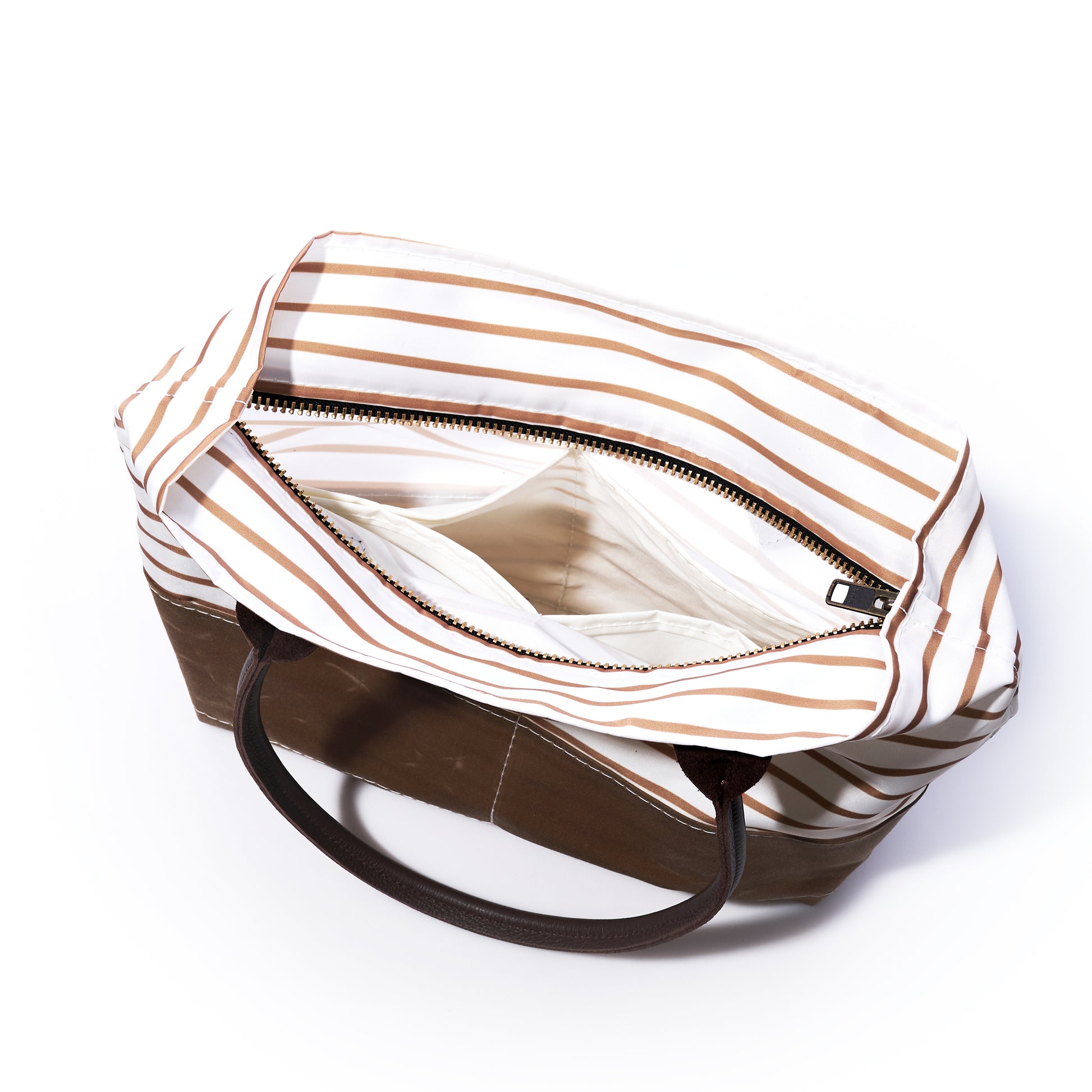 The Sea Bags Tan Chebeague Stripe Handbag is displayed open against a white background, revealing its spacious interior and zippered pocket. Crafted from recycled sail cloth and featuring brown handles, this bag takes inspiration from Chebeague Island. by Sea Bags