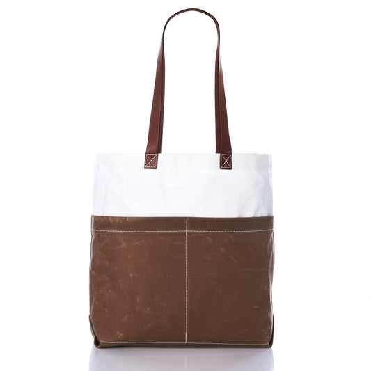 The Sea Bags Tan Chebeague Market Tote, featuring durable brown and white waxed canvas, two long brown handles, and an exterior front pocket, is pictured against a white background. Inspired by the classic Chebeague Market Tote, this stylish bag combines timeless appeal with everyday durability. by Sea Bags