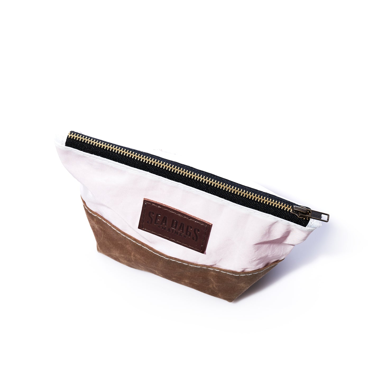 Introducing the Tan Chebeague Cosmetic Bag by Sea Bags—a small, two-tone zippered pouch expertly crafted from recycled sailcloth. Featuring a white upper section, a tan base, and the signature SEA BAGS label on the front, it’s perfect for use as a cosmetic bag or travel accessory. by Sea Bags
