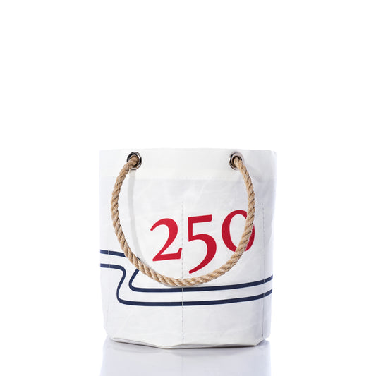 Handcrafted in Maine from recycled sail cloth, the Sea Bags 250th Patriotic Beverage Bucket Bag features a white bucket-style design with sturdy rope handles, accented by a bold red 250 and blue lines as part of the USA 250 Collection. The bag is displayed against a white background. by Sea Bags