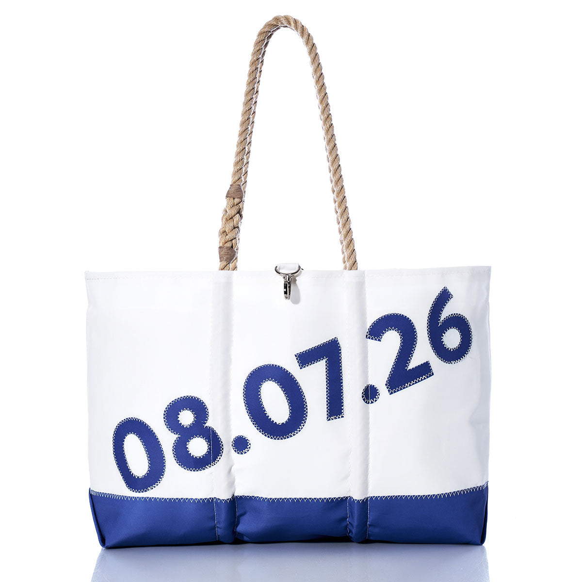 A white and blue Sea Bags Custom Date Ogunquit Beach Tote with rope handles, crafted from recycled sailcloth and featuring large blue numbers “08.07.26” displayed diagonally across the front, is shown against a white background. This personalized tote is perfect for commemorating a special day by the sea. by Sea Bags