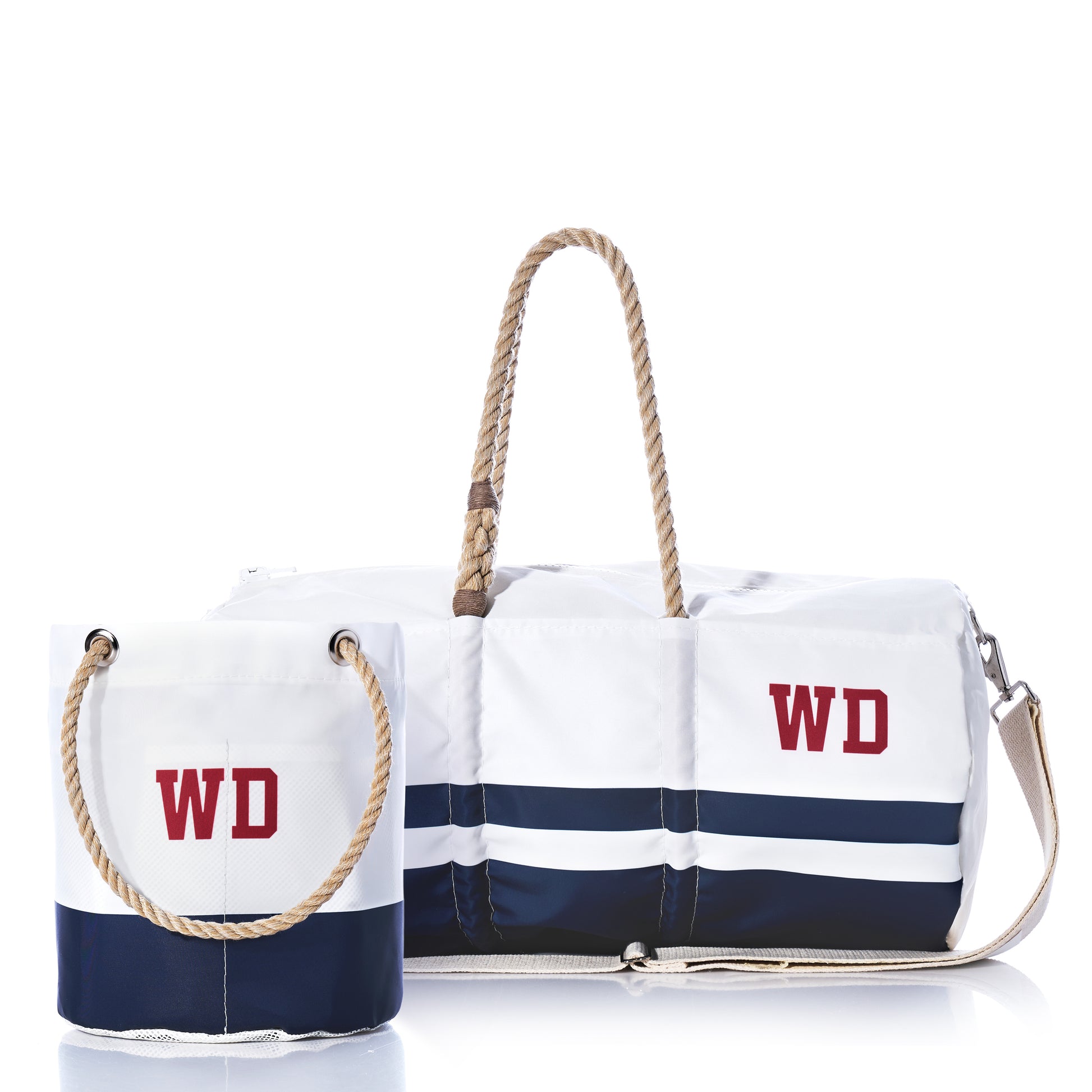 The Sea Bags Custom Monogram Breton Stripe Duffel  Bucket Bundle features two recycled sailcloth bags—one a tote-style bucket bag, the other a personalized duffel with an adjustable shoulder strap. Both showcase white and navy stripes and the red WD monogram, combining nautical charm with eco-friendly style for effortless travel or seaside weekends.