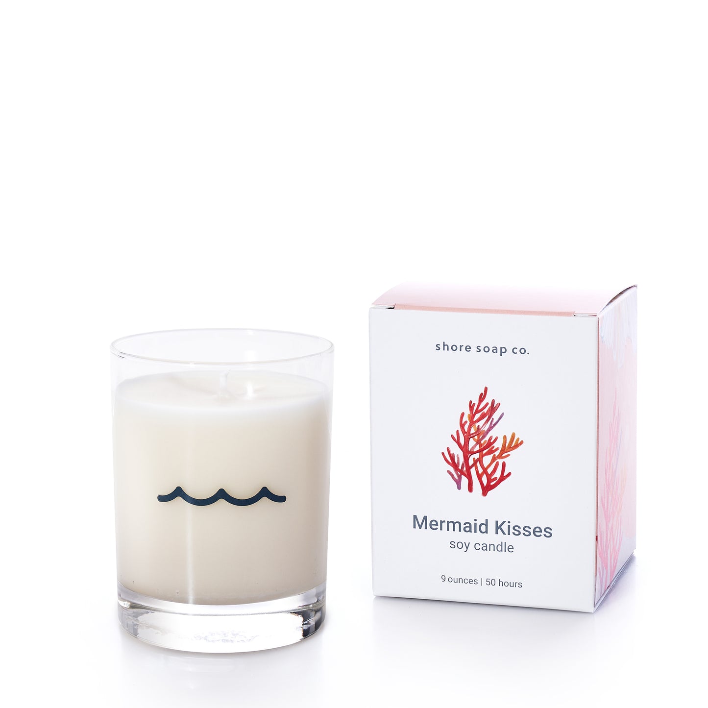 A white soy wax candle with a wave design in a clear glass sits beside its box, labeled “Mermaid Kisses Eco-Friendly Candle” by Shore Soap Co., and adorned with a red coral illustration—part of their handcrafted personal care collection.