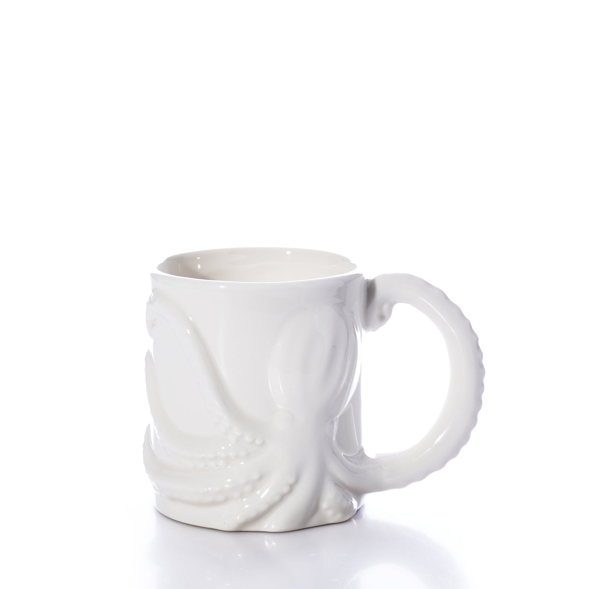 The White Octopus Mug by Batela USA Inc is a white ceramic mug with a raised octopus design, featuring one tentacle as the handle, and is shown against a plain white background. by Sea Bags