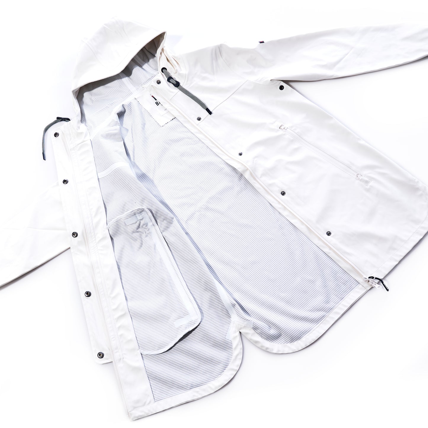 Harborside Waterproof Raincoat - White by Batela USA Inc laid flat, unzipped to reveal its inner mesh lining, side pockets, and snap button closures—a lightweight raincoat with a waterproof shell thats perfect for coastal weather. by Sea Bags