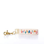 The Rustic Marlin Keychain - Downeast Buoys by Rustic Marlin features playful buoy illustrations on fabric with a gold metal clasp and ring, making it a charming canvas bag accessory that adds a whimsical, nautical touch to your everyday style. by Sea Bags