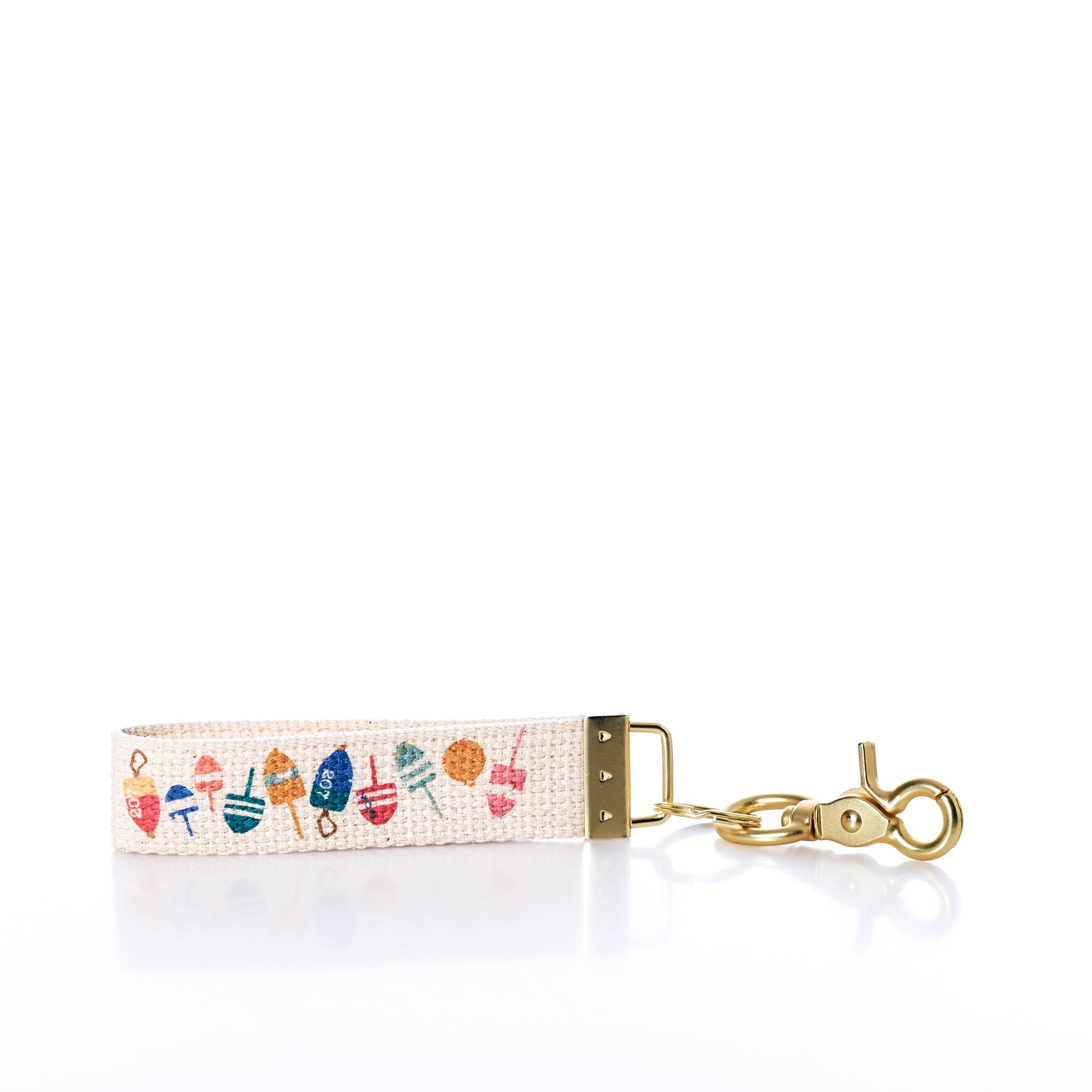 The Rustic Marlin Keychain - Downeast Buoys by Rustic Marlin features a colorful, abstract pattern inspired by coastal buoys, complemented with gold metal hardware and a lobster clasp—ideal as a cheerful accessory for your canvas bag or as a playful maritime keychain—shown against a pristine white background with light reflections. by Sea Bags