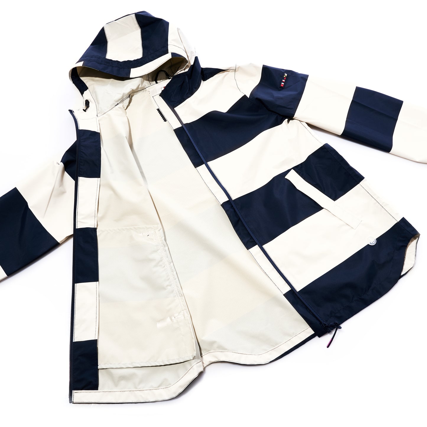 The Harborside Waterproof Raincoat by True is a women’s hooded raincoat with a waterproof shell, featuring wide navy and white horizontal stripes, a zippered front, long sleeves, and large front pockets. It is laid flat with the left side open to show the interior.