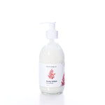 Shore Soap Co. Mermaid Kisses Eco-Friendly Body Lotion in a clear glass pump bottle with a white label featuring a red coral design, photographed on a white background. This natural body lotion provides nourishing care in an elegantly designed, eco-friendly package. by Sea Bags