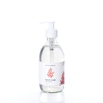 A clear pump bottle of Mermaid Kisses Eco-Friendly Liquid Soap by Shore Soap Co., featuring a white label with red coral illustrations, photographed on a white background. Made with natural ingredients, this gentle formula is ideal for sensitive skin.