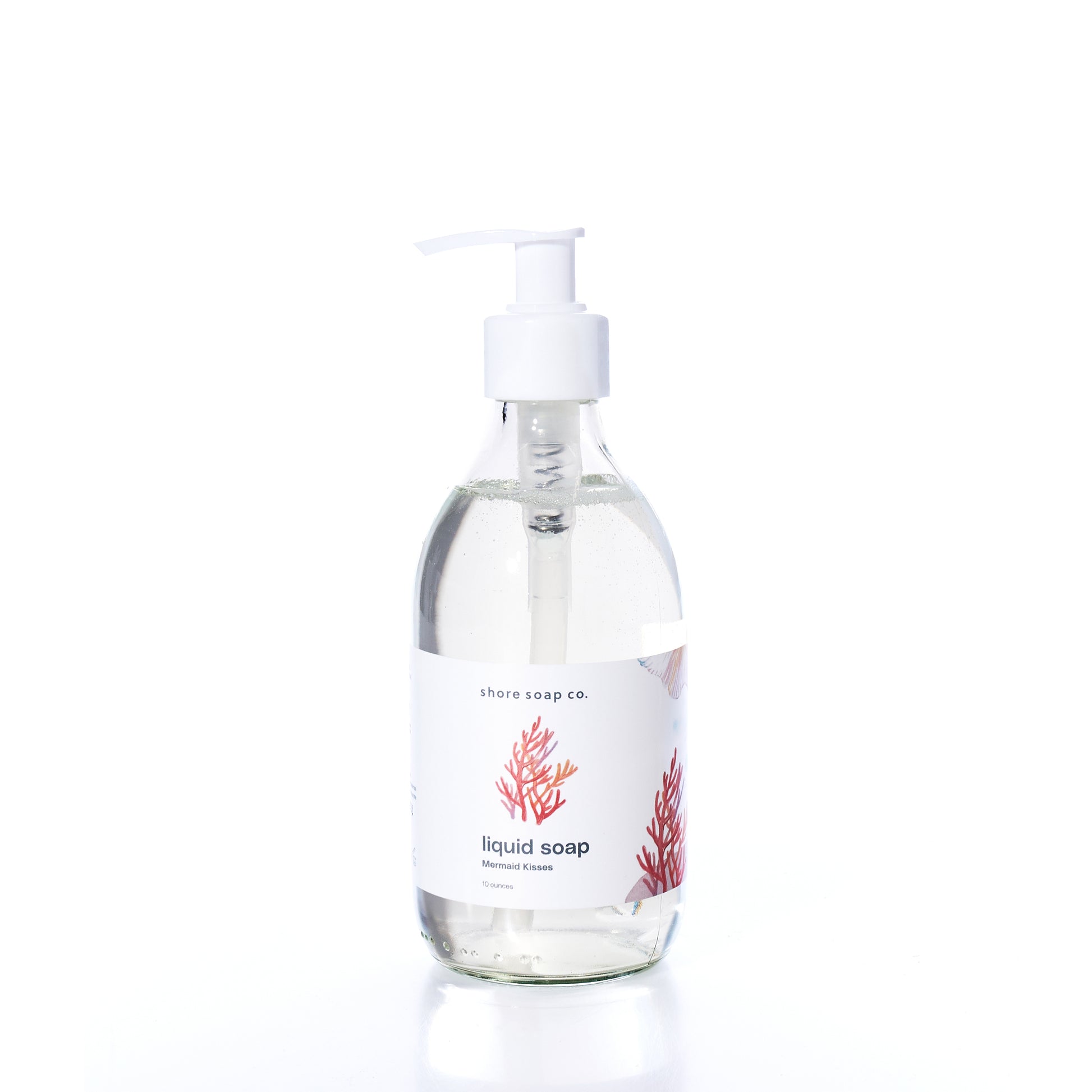A clear pump bottle of Mermaid Kisses Eco-Friendly Liquid Soap by Shore Soap Co., featuring a white label with red coral illustrations, photographed on a white background. Made with natural ingredients, this gentle formula is ideal for sensitive skin.