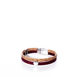 Introducing the Classic Cork Bracelet - Heart on Wine by Elisabetta Studio: This eco-friendly piece is handcrafted in Vermont, featuring a tan cork band paired with a dark red band, accented by a silver magnetic clasp and a delicate silver heart charm. Displayed on a white background, this bracelet beautifully blends sustainable style with heartfelt elegance—perfect for Valentines Day or any occasion. by Sea Bags