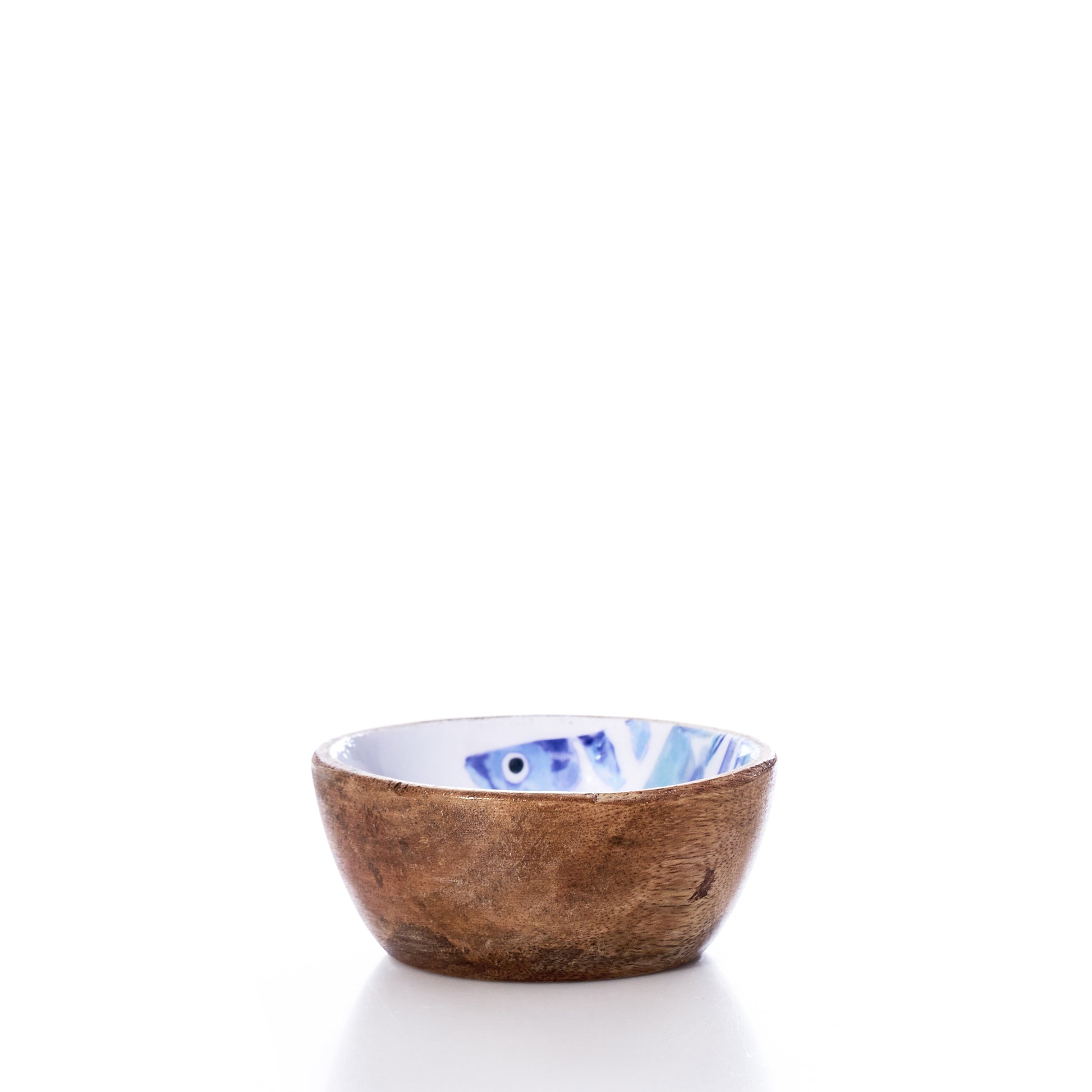 The Batela USA Inc Enameled Wood Bowl - Striped Fish is a small, round mango wood bowl featuring a brown textured exterior and a white enameled interior adorned with a blue striped fish design. Set against a white background, this charming bowl brings a subtle nautical touch to any table setting. by Sea Bags