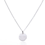 Elevate your jewelry collection with the Pendant Necklace - Horizon Silver by Maine Yoga Jewelry: a refined silver chain showcasing a round, textured silver pendant accented with a distinctive horizontal line detail, beautifully presented against a white background. by Sea Bags