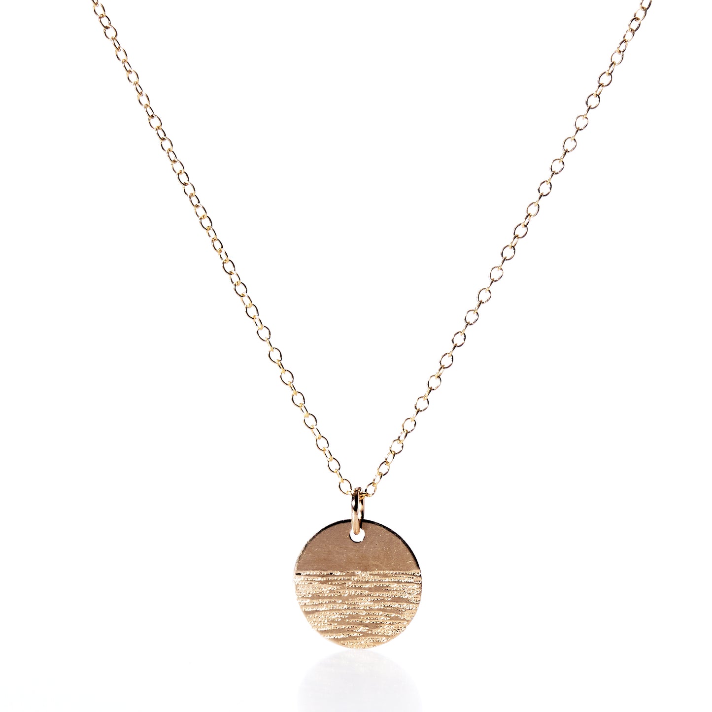 The Pendant Necklace - Horizon Gold by Maine Yoga Jewelry features a fine gold chain and a round, textured gold pendant, beautifully photographed on a white background—an exquisite addition to any jewelry collection. by Sea Bags