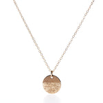 The Pendant Necklace - Horizon Gold by Maine Yoga Jewelry features a fine gold chain and a round, textured gold pendant, beautifully photographed on a white background—an exquisite addition to any jewelry collection. by Sea Bags
