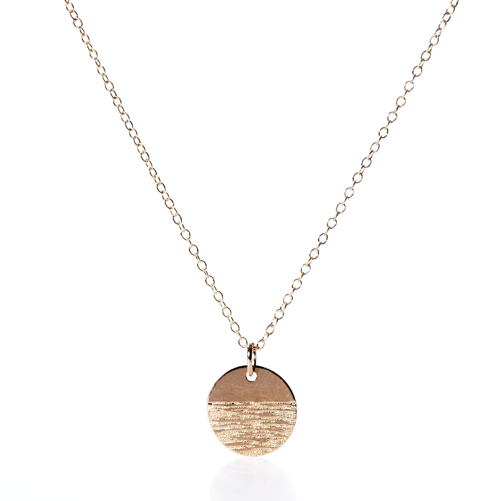 The Pendant Necklace - Horizon Gold by Maine Yoga Jewelry features a fine gold chain and a round, textured gold pendant, beautifully photographed on a white background—an exquisite addition to any jewelry collection. by Sea Bags