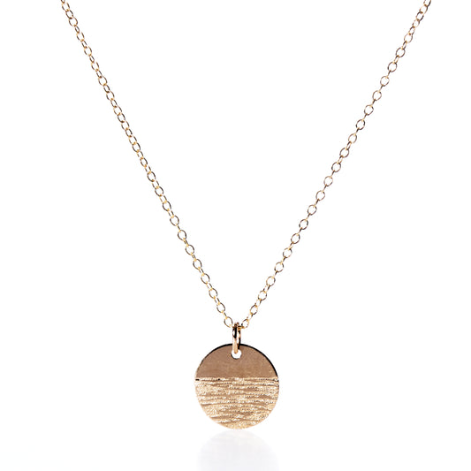 The Pendant Necklace - Horizon Gold by Maine Yoga Jewelry features a fine gold chain and a round, textured gold pendant, beautifully photographed on a white background—an exquisite addition to any jewelry collection. by Sea Bags