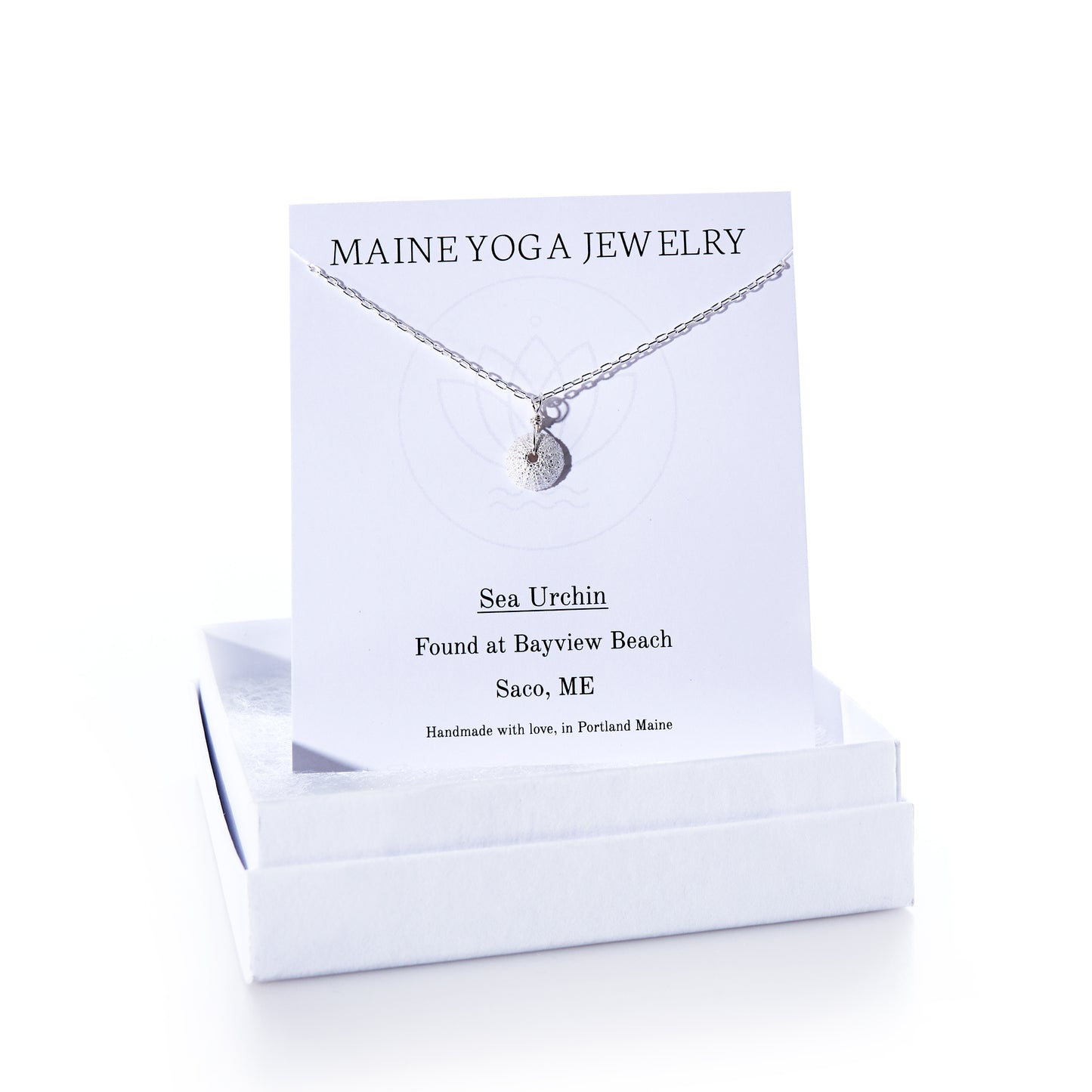 The Pendant Necklace - Tiny Sea Urchin Silver by Maine Yoga Jewelry features a handcrafted silver sea urchin pendant on a delicate silver chain, beautifully displayed on a branded Maine Yoga Jewelry card and presented in an elegant white jewelry box. by Sea Bags