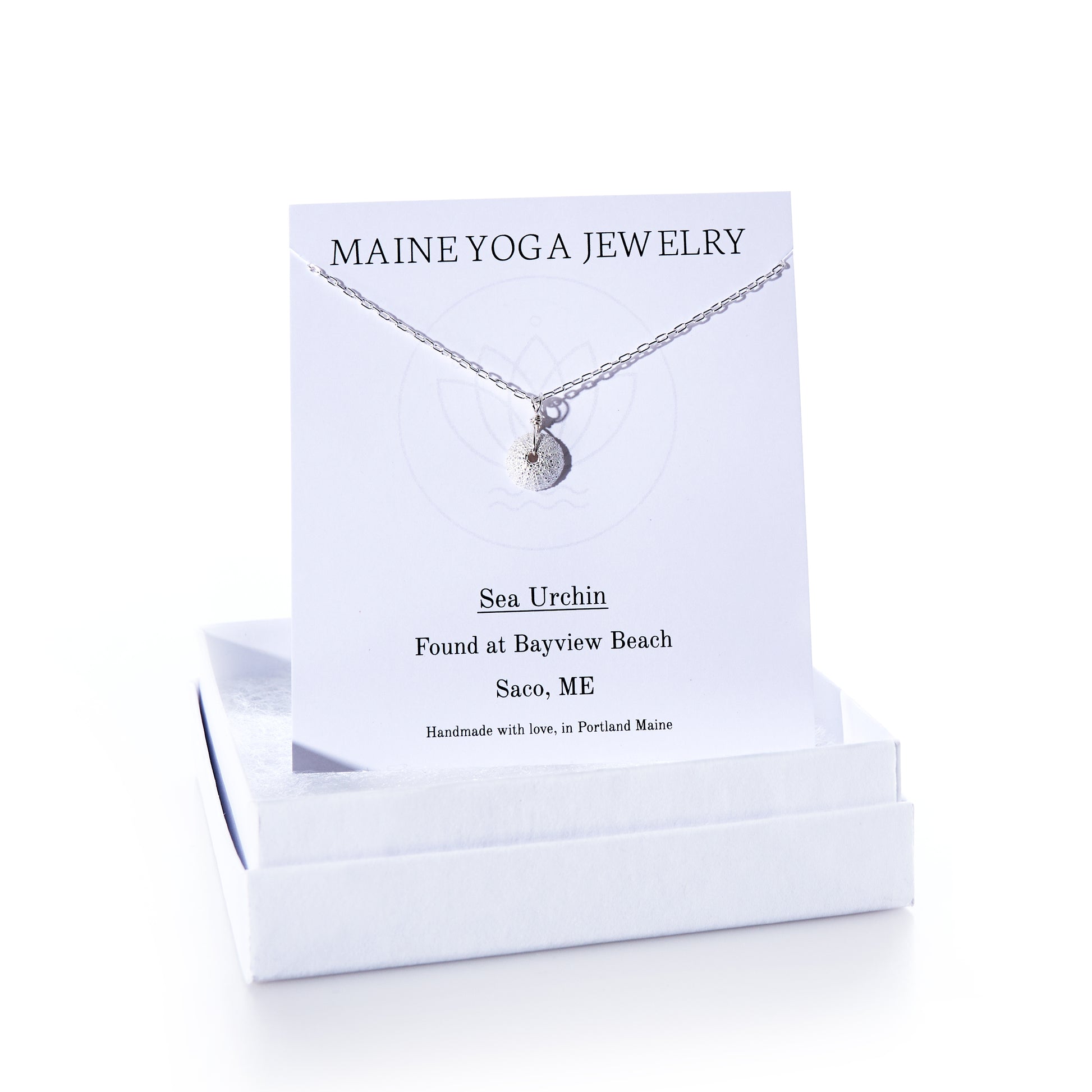 The Pendant Necklace - Tiny Sea Urchin Silver by Maine Yoga Jewelry features a handcrafted silver sea urchin pendant on a delicate silver chain, beautifully displayed on a branded Maine Yoga Jewelry card and presented in an elegant white jewelry box. by Sea Bags