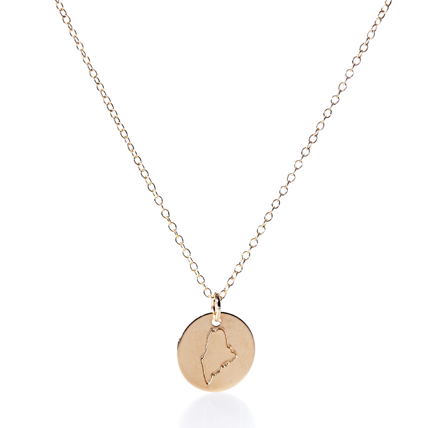 Pendant Necklace - Gold Maine by Maine Yoga Jewelry features a round gold charm engraved with the outline of Maine, artfully displayed on a plain white background. Expertly crafted in Maine, this piece showcases timeless elegance and distinctive craftsmanship. by Sea Bags