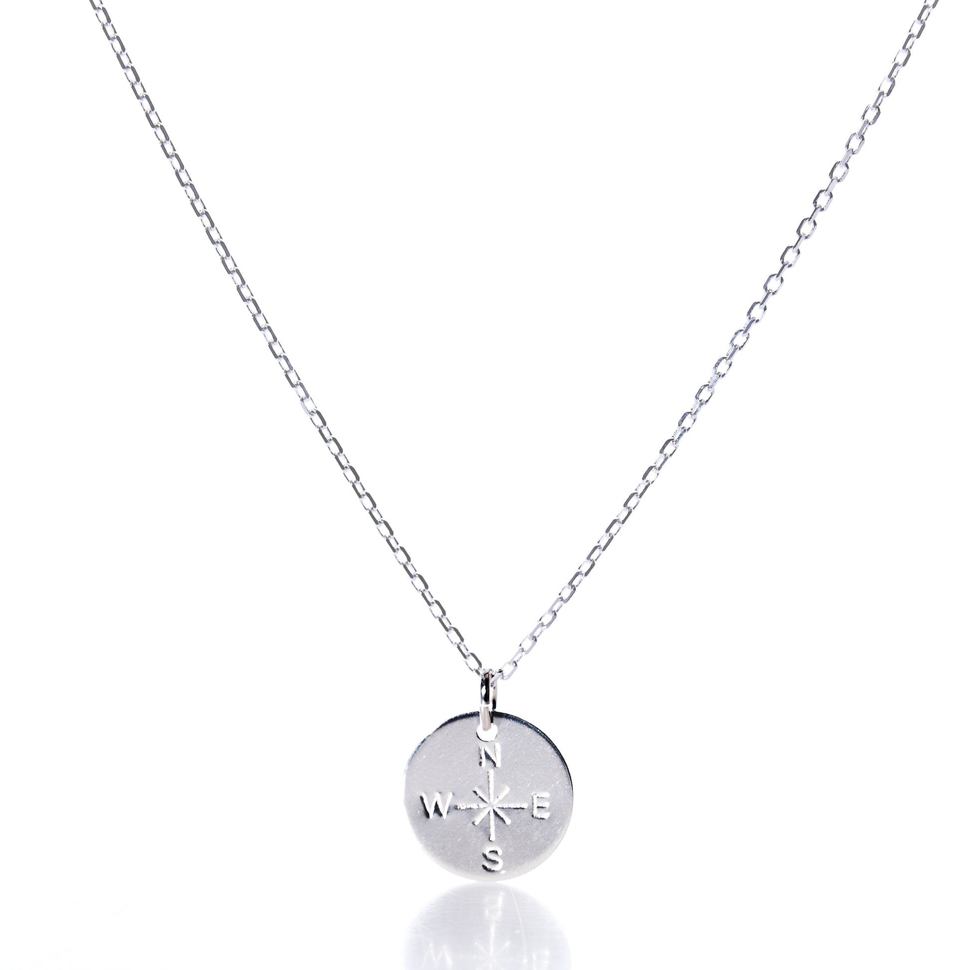 Discover the Pendant Necklace - Silver Compass Rose by Maine Yoga Jewelry, featuring a round silver pendant engraved with a compass rose showing N, S, E, and W directions. This nautical necklace is displayed on a simple chain against a white background and is proudly made in Maine. by Sea Bags
