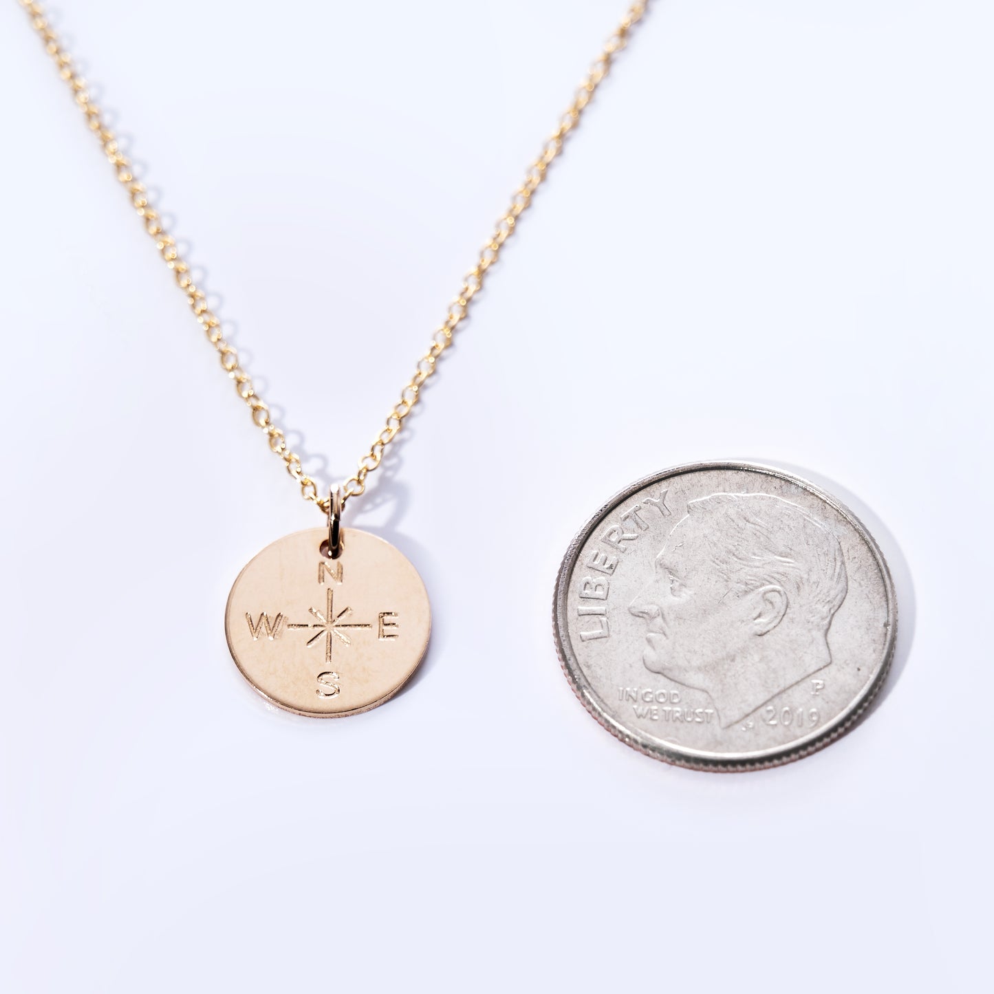 Pendant Necklace - Gold Compass Rose by Maine Yoga Jewelry shown beside a 2019 US dime on a white background to illustrate the pendant’s size. This nautical necklace is expertly crafted and proudly made in Maine. by Sea Bags