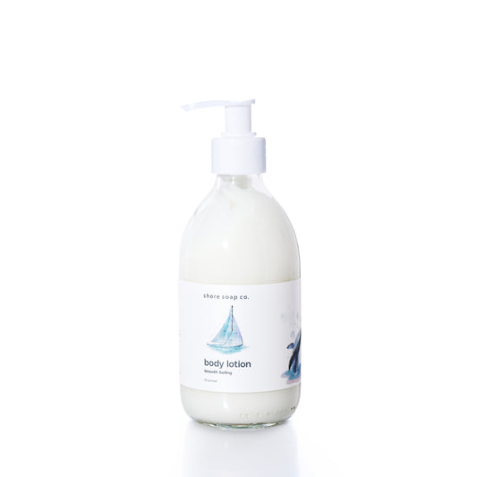 Smooth Sailing Eco-Friendly Body Lotion by Shore Soap Co is presented in a clear glass pump bottle with a white label adorned with a sailboat illustration, photographed on a white background. Ideal for sensitive skin, this natural formula delivers lasting moisture while nourishing your body. by Sea Bags