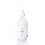 A clear pump bottle of true Warm Sand Eco-Friendly Body Lotion with a white label featuring a seashell graphic, photographed on a white background. Formulated with natural oils to help hydrate dry skin, this lotion provides nourishment while supporting sustainability.