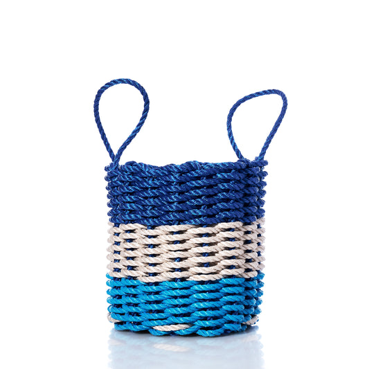 A small, eco-friendly Fisherman Rope Basket by Advanced Industrial Solutions Inc, featuring two handles and horizontal bands in blue, light blue, and tan—crafted with classic Maine-inspired techniques and set against a white background. by Sea Bags