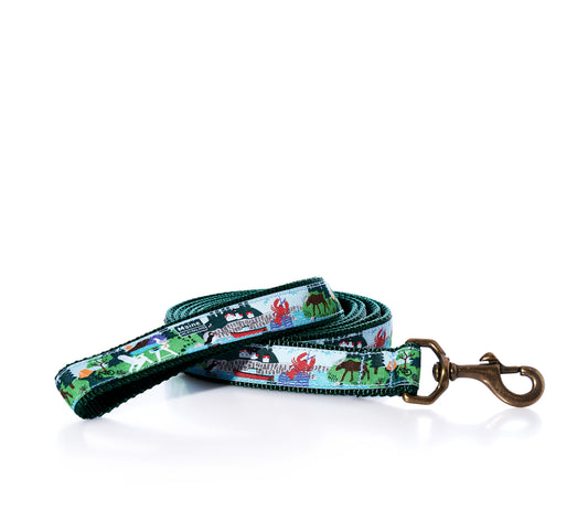 The Belted Cow Vacationland Dog Leash, crafted from heavy-duty nylon, showcases a vibrant Maine-inspired pattern with animals and scenic landscapes. It features a robust metal clip at one end and is presented rolled up on a white background. by Sea Bags