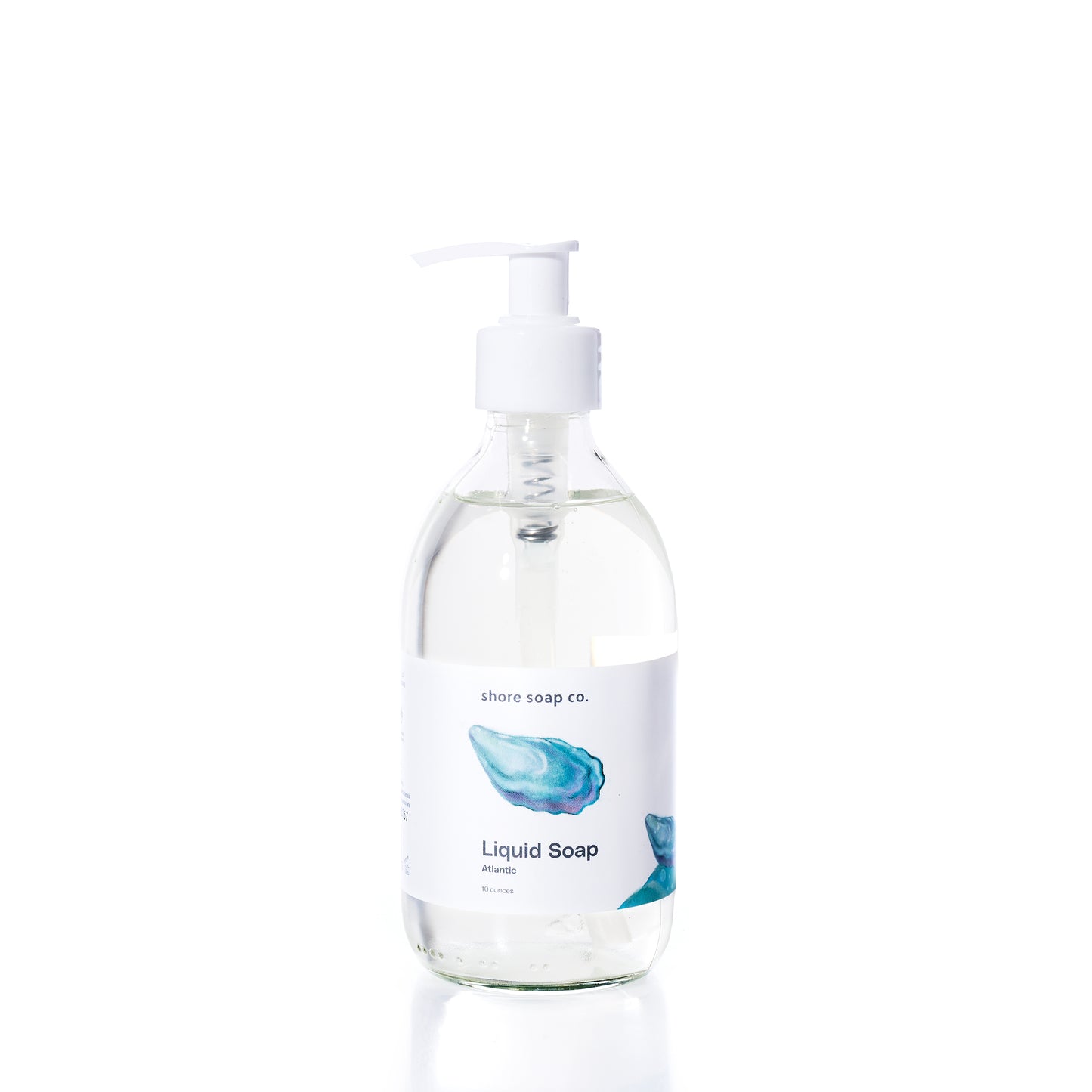 Clear pump bottle of Shore Soap Co. Atlantic Eco-Friendly Liquid Soap with a white label featuring blue watercolor art and the text Atlantic Eco-Friendly Liquid Soap on a white background. This gentle, pH-balanced formula is sulfate-free, making it perfect for everyday use. by Sea Bags
