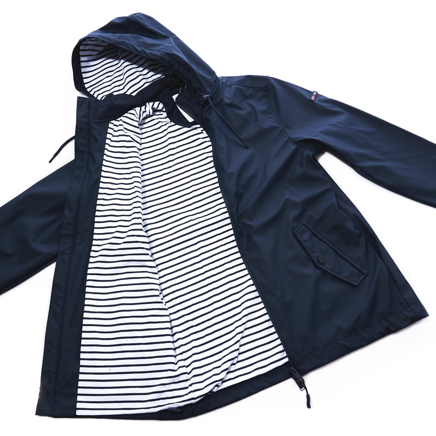 Batela USA Inc Waterproof Raincoat Button Pocket - Navy, a unisex navy blue raincoat featuring a hooded, waterproof shell, button closure, two side pockets, and a white and black striped inner lining, displayed open on a white background. by Sea Bags