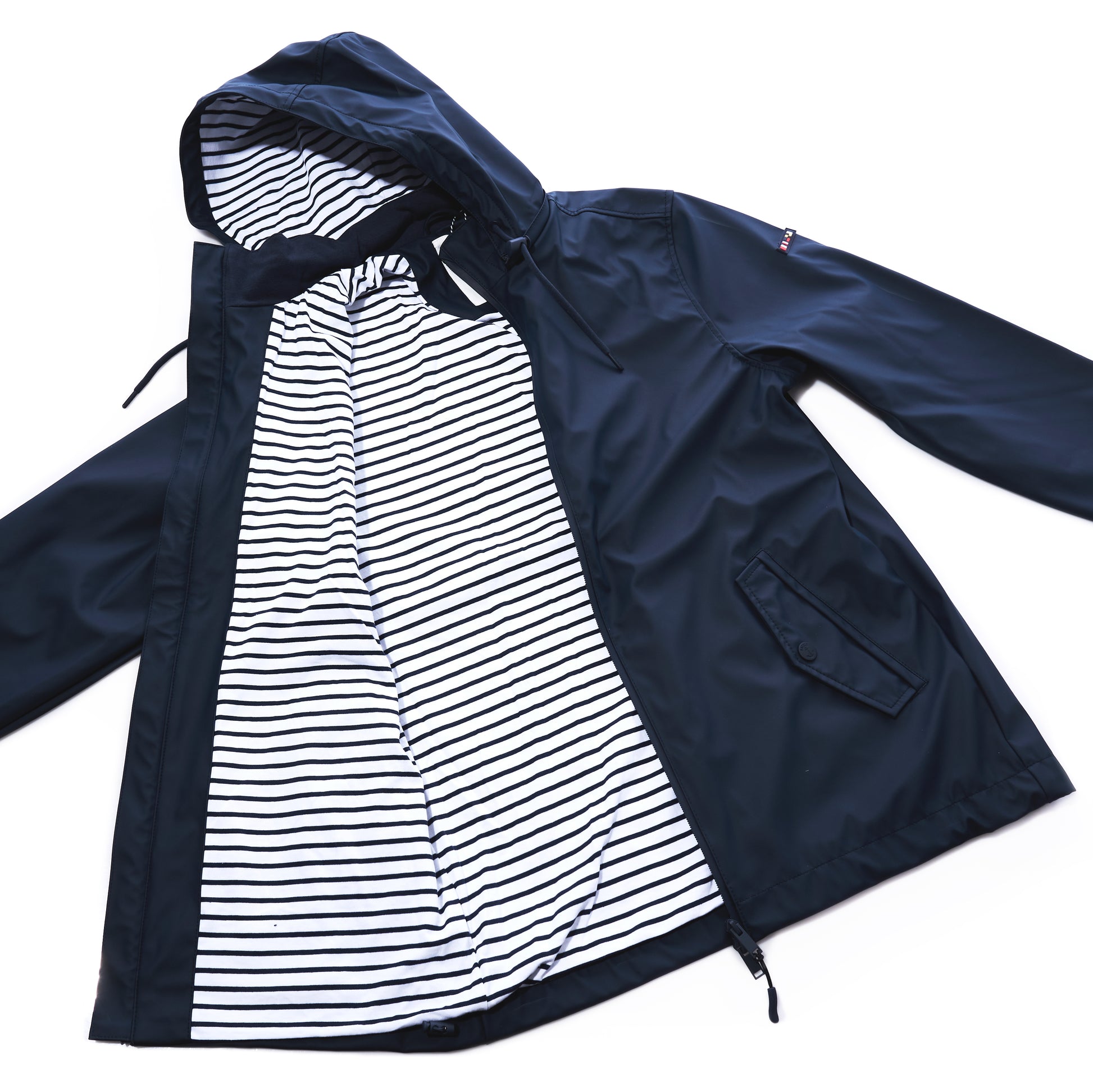 Batela USA Inc Waterproof Raincoat Button Pocket - Navy, a unisex navy blue raincoat featuring a hooded, waterproof shell, button closure, two side pockets, and a white and black striped inner lining, displayed open on a white background. by Sea Bags