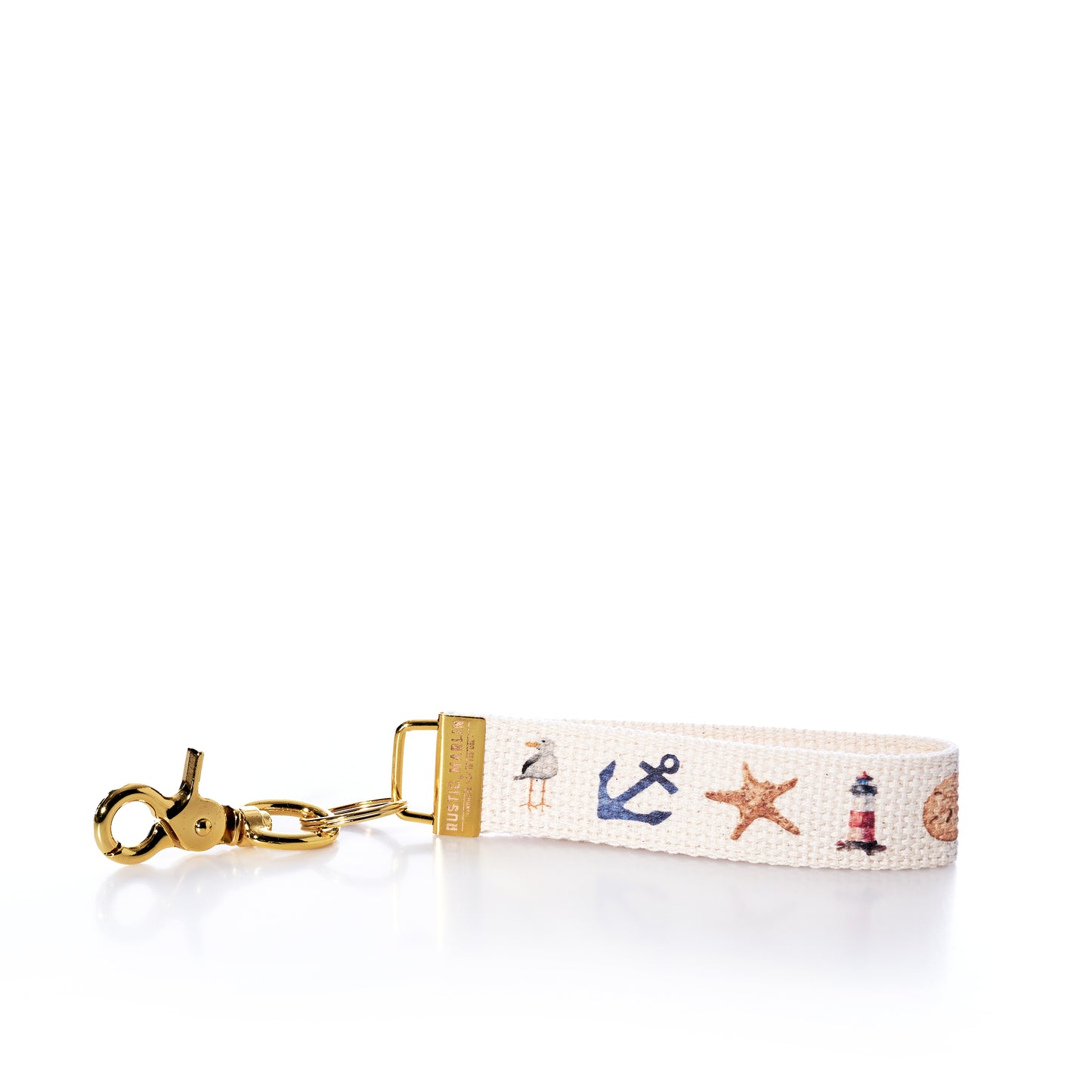 Introducing the Rustic Marlin Keychain - Summer Icons from Rustic Marlin. This keychain wrist strap showcases nautical-themed icons such as an anchor, starfish, lighthouse, and seashell printed on a white fabric band, complete with a gold clasp. The versatile design makes it perfect not just as a keyholder but also as a stylish bag charm or a unique souvenir for your collection. by Sea Bags