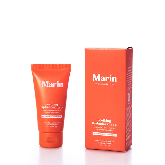 The Marin Skincare Mini Soothing Hydration Cream tube and its matching box are displayed on a white background. Both items, designed for use on the face, hands, and body, highlight Marine Glycoproteins—ingredients known to support skin repair and provide long-lasting hydration. by Sea Bags