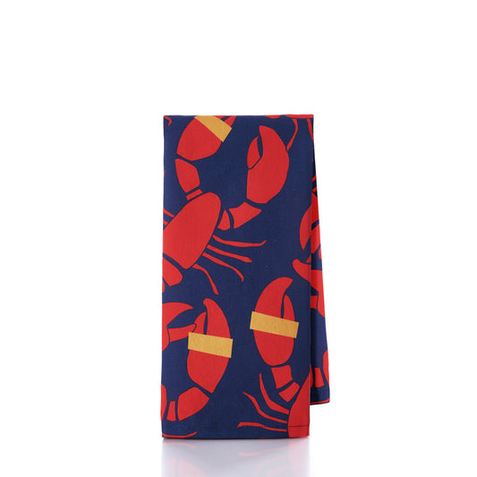 The Boston International Lobster Bake Tea Towel features a navy blue fabric adorned with a red lobster pattern and yellow bands on the claws, evoking the charm of a classic lobster bake, shown against a white background. by Sea Bags
