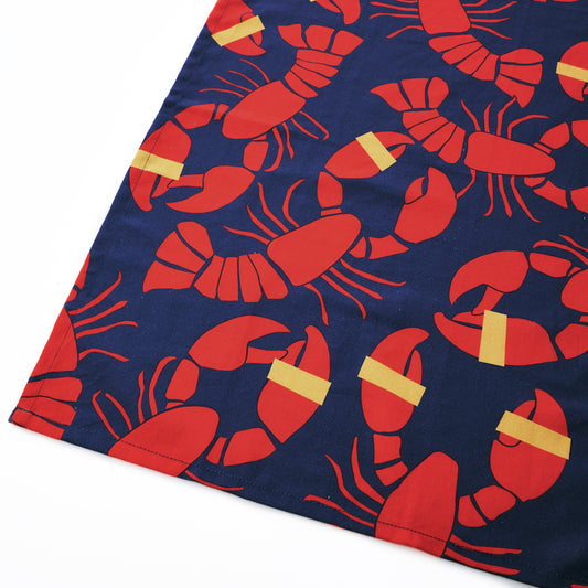 Add a touch of coastal charm to your kitchen with the Lobster Bake Tea Towel by Boston International, featuring a navy blue fabric adorned with a repeating pattern of red lobsters and yellow bands around their claws—perfect as a hostess gift or as an accent for your next lobster bake. by Sea Bags