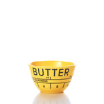 The Butter Dipping Bowl by Merritt International Inc dba Merritt Designs is a yellow plastic bowl labeled BUTTER, featuring measurement markings and a note indicating NOT MICROWAVE. Perfect for your next seafood indulgence as a lobster bake bowl, it is shown set against a white background. by Sea Bags