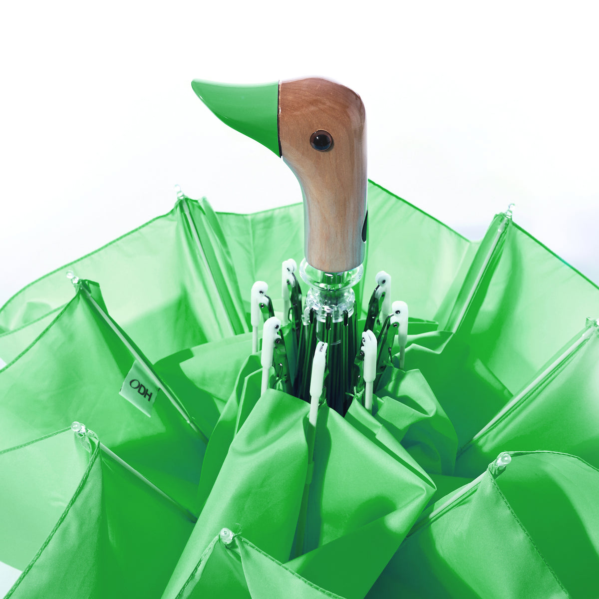 The Original Duck Head Umbrella - Matcha Green, a sustainable umbrella crafted from recycled plastic with a signature duck-shaped handle, is partially opened against a white background.